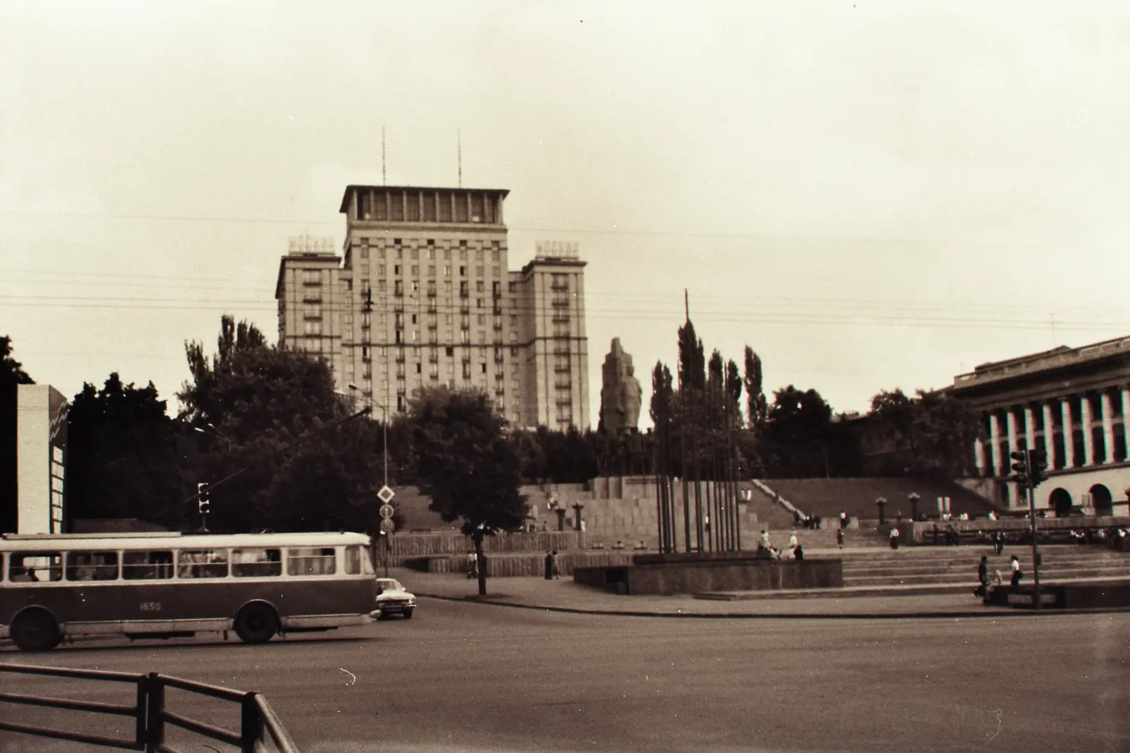 A man on a park path with a church dome in the distance