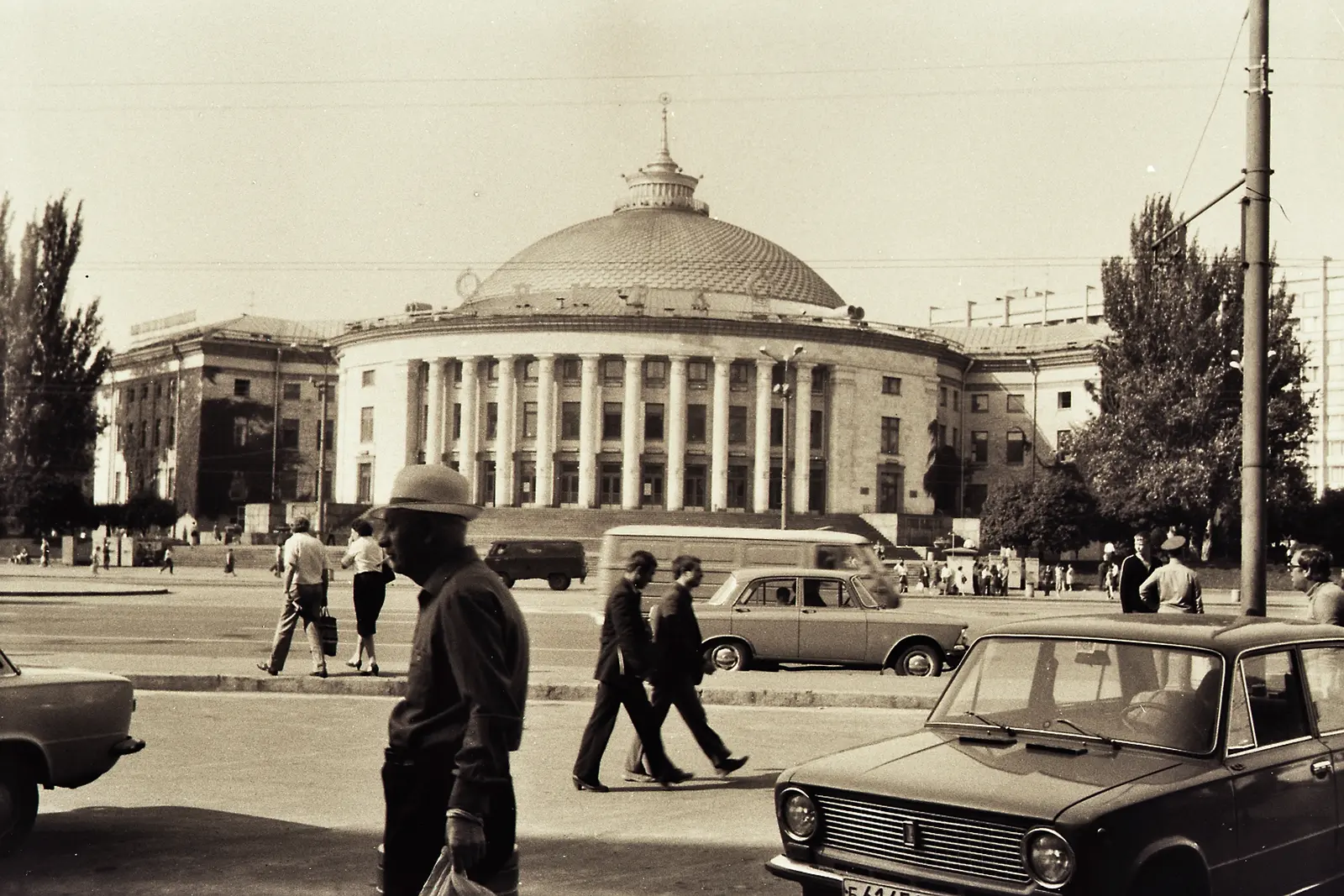 Two men talking in front of the colonnaded university building