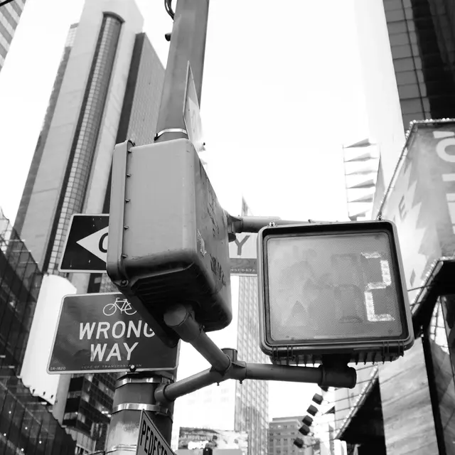 Wrong Way sign and crosswalk signal against Midtown towers