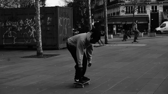 Skater bombing a hill past a graffitied container