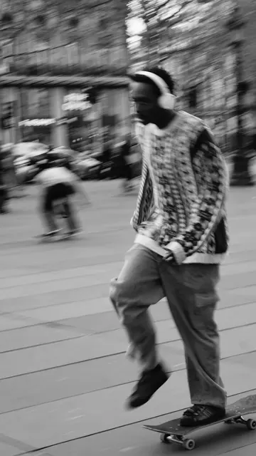 Skater in headphones cruising, motion blur across the square