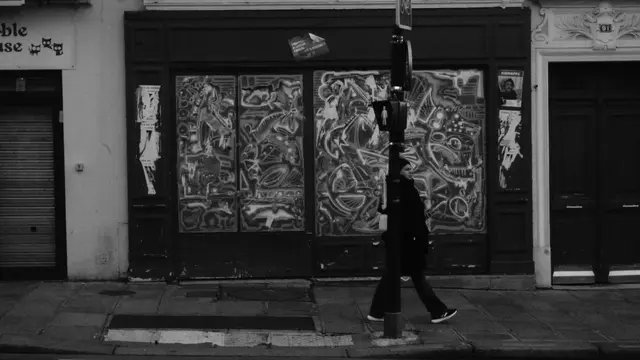 Woman passing a shopfront covered in psychedelic paintings