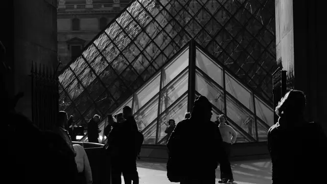 Silhouettes against the glass of the Louvre pyramid