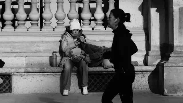 A jogger passing a family resting on a stone bench at the Louvre