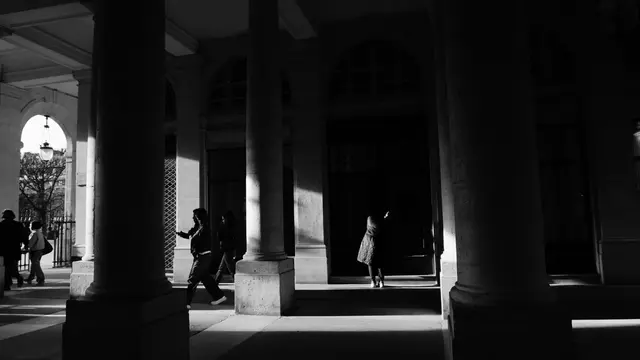 Figures crossing the light between the Palais-Royal columns