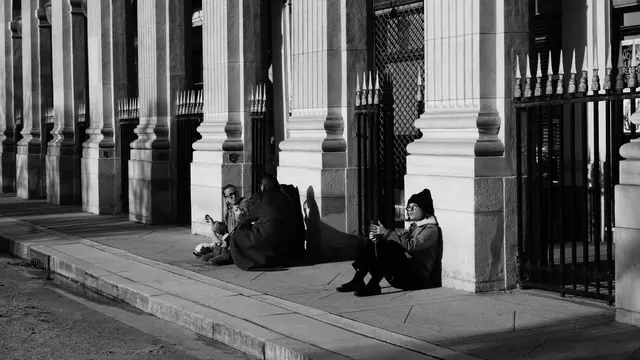 People sitting in the winter sun along the Palais-Royal railings