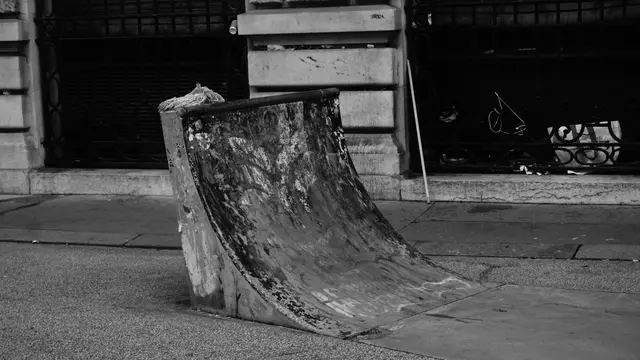 A battered mini quarter-pipe left on the sidewalk
