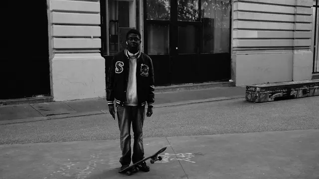 Young skater standing over his board, looking at the camera