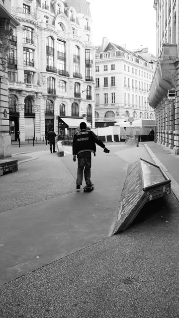 Skater rolling toward a ledge in a grand Paris street