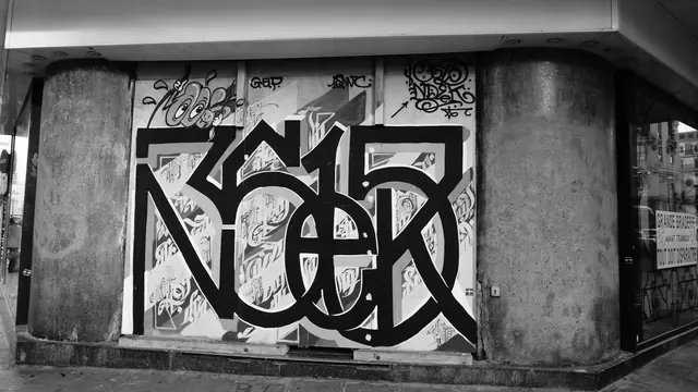 Bold black-and-white graffiti piece on a boarded corner