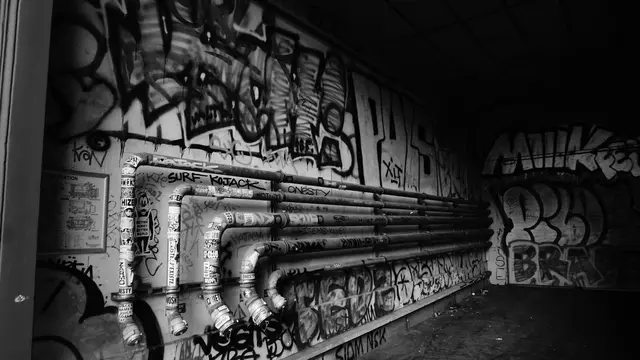 Tagged pipes and stickers in a graffiti-covered underpass