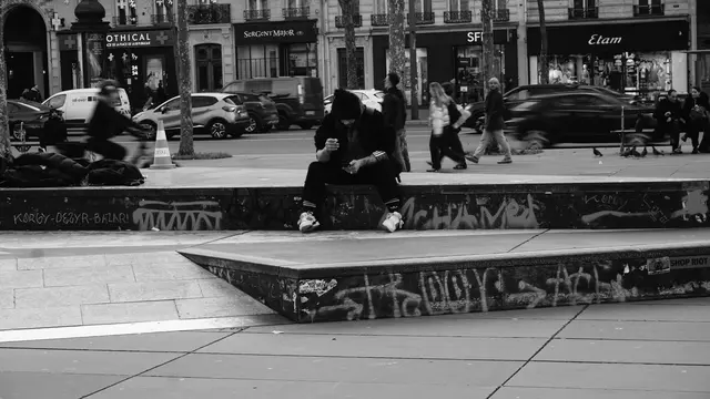 A figure rolling a cigarette on the ledges of Place de la République