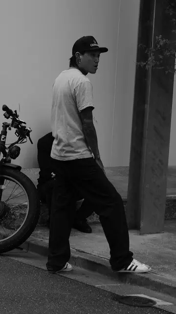 Tattooed guy in a cap glancing back on the curb
