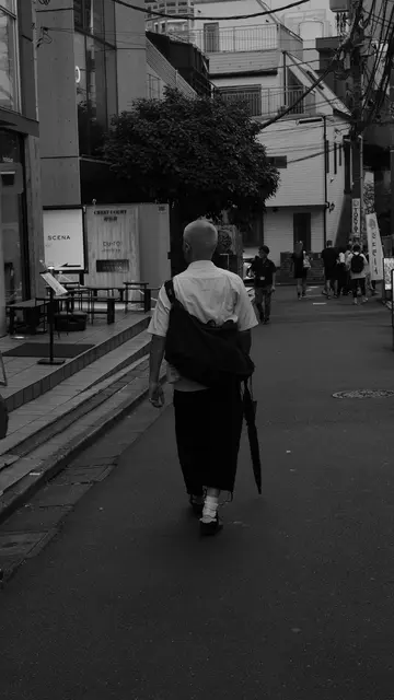 Bleached buzzcut walking a Jingumae backstreet, umbrella in hand
