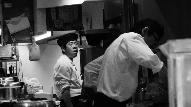 Cooks caught mid-shift in a small kitchen