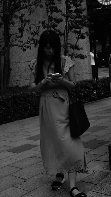 Woman in a lace dress checking her phone on the sidewalk
