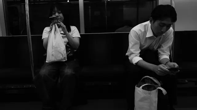 Two passengers on the last train, both lost in their phones