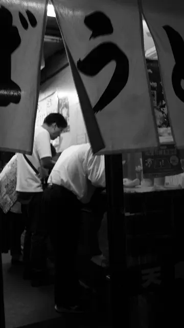 Diners glimpsed through the noren curtains of an udon joint
