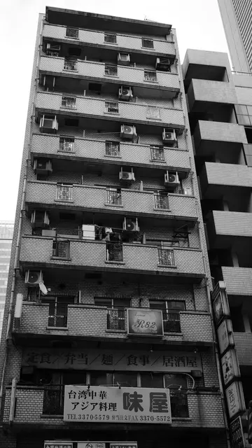 Narrow apartment block stacked with balconies and AC units