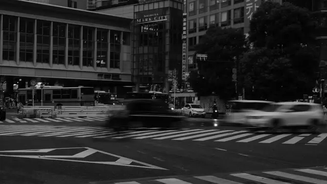 Cars streak past Shibuya Mark City at dusk